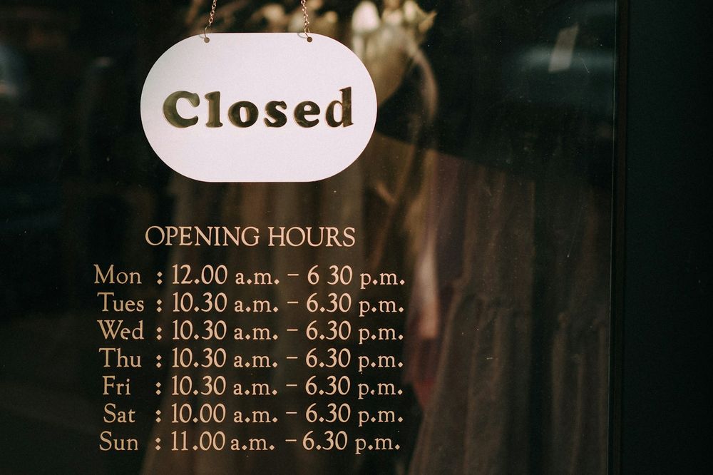 Closed sign and opening hours posted on a shop window